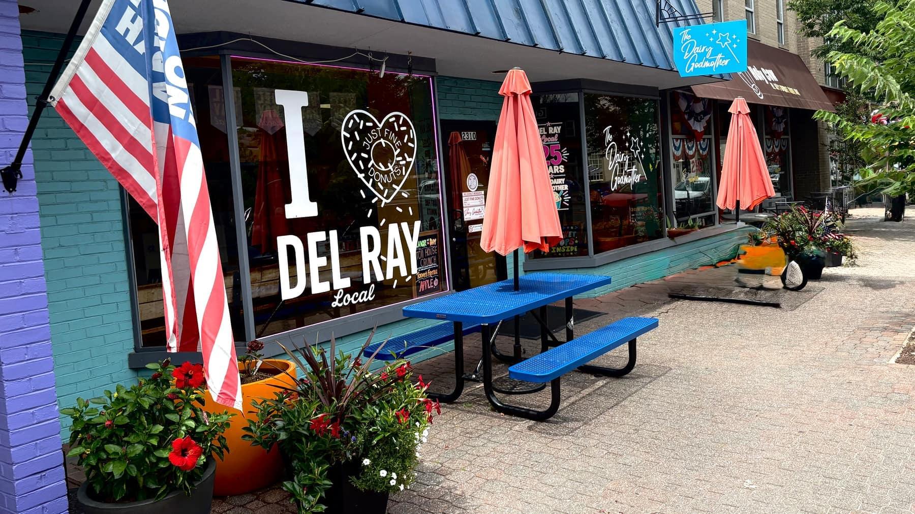 A colorful 'I Love Del Ray' storefront window on Mount Vernon Avenue, flags and flowers out front