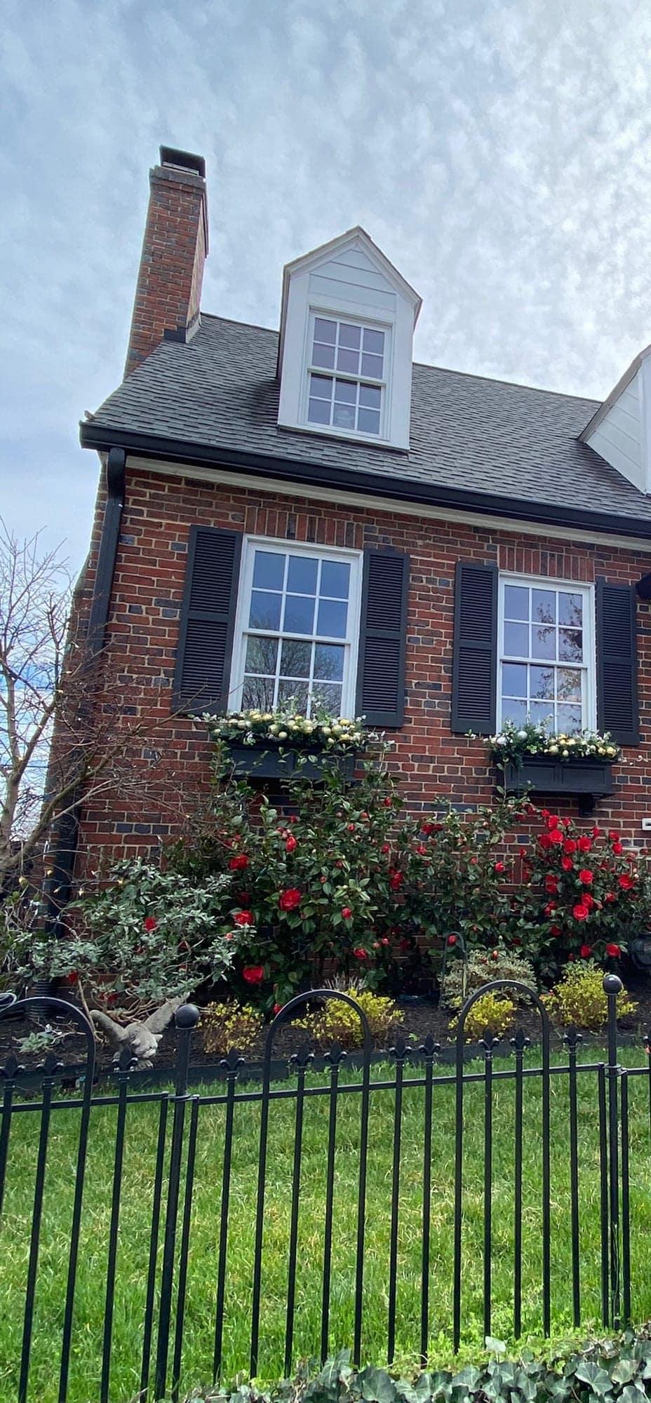 A brick Rosemont-area home with dormer windows and blooming rose bushes