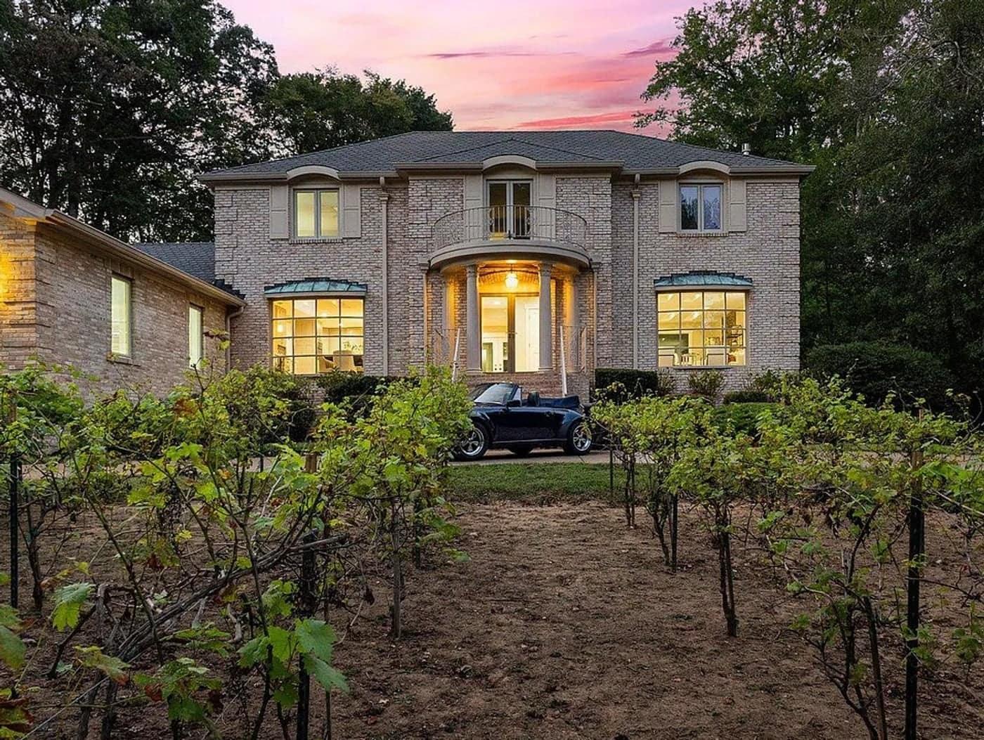 A Hallowing Point home in Mason Neck at dusk, seen past rows of grapevines in the front garden