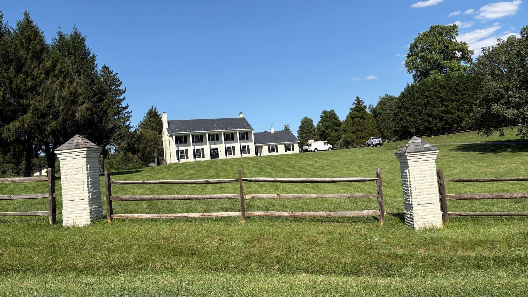 A well-kept brick and cream colonial home in Mason Neck, shaded by mature trees with a manicured lawn and brick walkway
