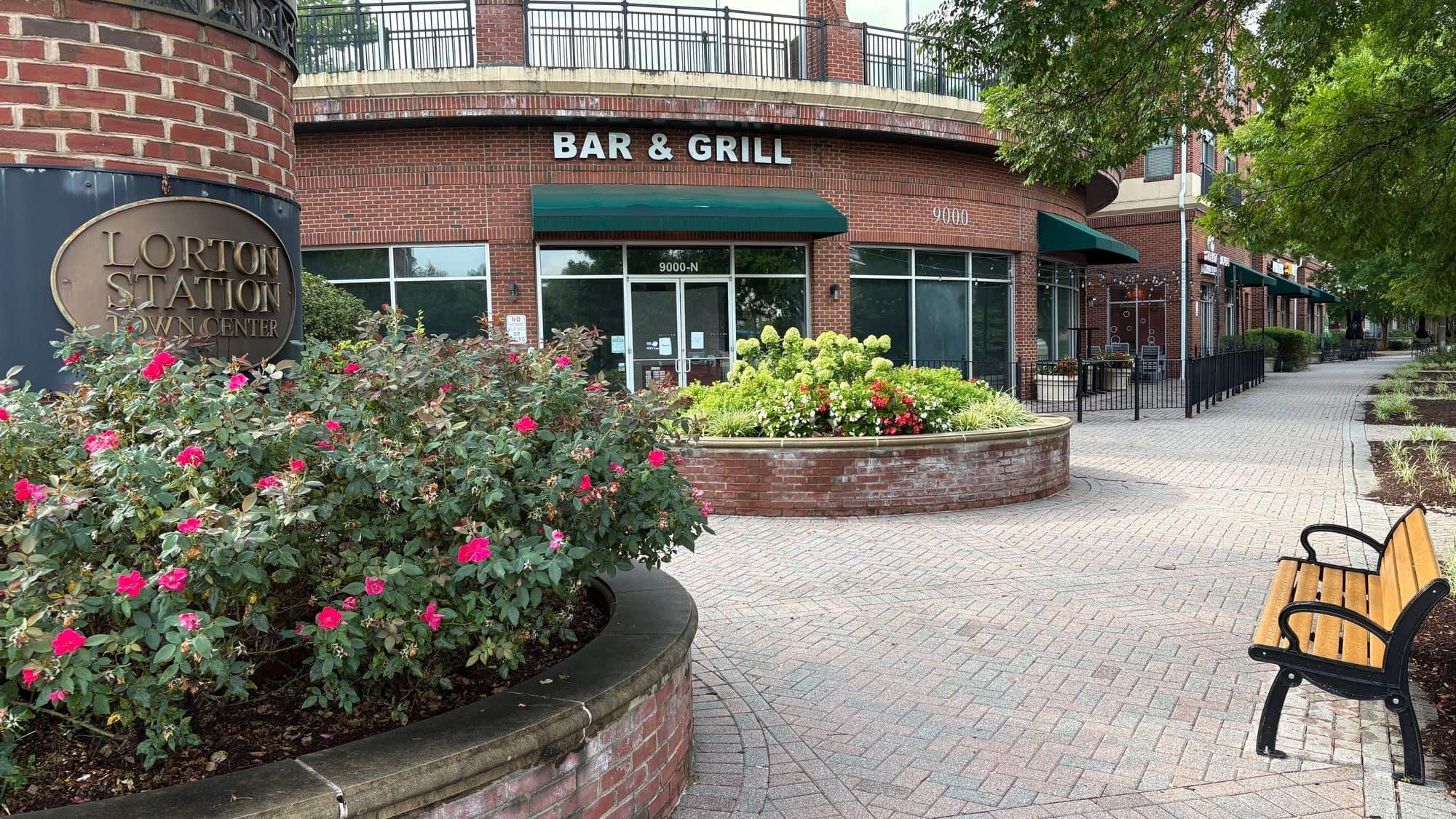 The Lorton Station Town Center sign beside a rose-lined restaurant plaza