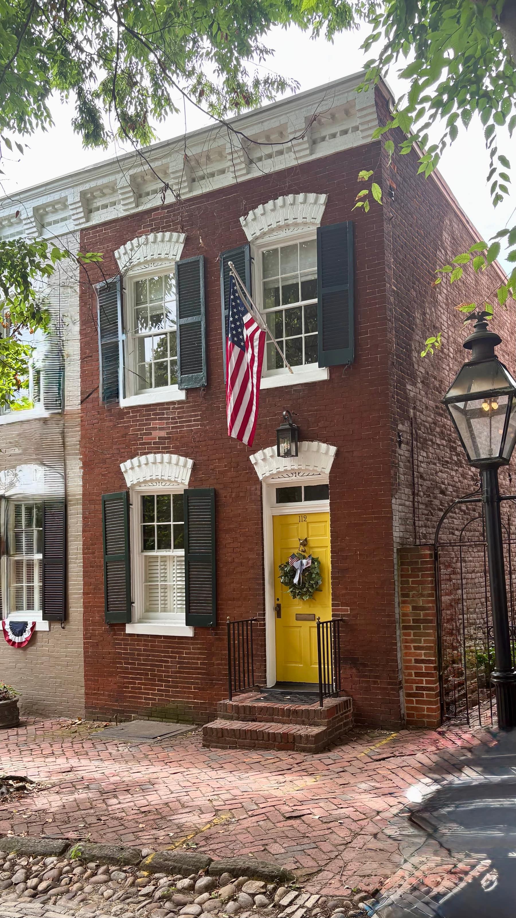A classic Old Town Alexandria rowhouse with an American flag over a yellow door